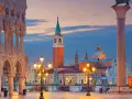 Piazza San Marco a Venezia al tramonto, con il Palazzo Ducale, il Campanile e la Basilica di San Giorgio Maggiore illuminati.