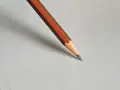 Ołówek do pisma technicznego, z pomarańczowo-brązową obudową, gotowy do precyzyjnych kresek na białym papierze.