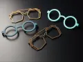 Four colorful, modern 3d printing glasses frames in geometric and round shapes, displayed on a dark surface.