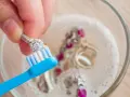 Limpia tu plata con bicarbonato y vinagre. Un anillo de diamantes se cepilla suavemente en un bol con joyas burbujeantes.