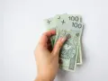 Dłoń trzyma banknoty 100 zł. To 300 zł, wystarczające na wiele przyjemności, nawet dla osoby w każdym wieku.