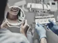 Dentysta pokazuje pacjentce wzornik kolorów zębów, pacjentka ogląda swój uśmiech w lusterku.