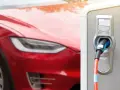 Czerwona Tesla podłączona do ładowarki. Czas ładowania zależy od modelu i mocy stacji.