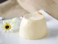 Delizioso budino fatto in casa, servito su un piatto bianco con un fiore decorativo.