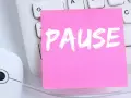 Ein rosa Zettel mit dem Wort "PAUSE" liegt auf einer Tastatur neben einer Maus. Ein Hinweis auf das **bildschirmpause gesetz**.