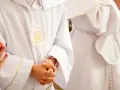 Dzieci w białych albach z haftem IHS czekają na swoją pierwszą komunię świętą.