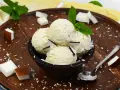 Schüssel mit cremigem Kokoseis, garniert mit Kokosraspeln und Minze. Perfekt, um Kokoseis selber zu machen!