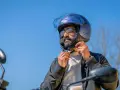 Uomo con barba che indossa un casco da moto blu iridescente, pronto per un giro.