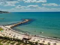 Piękna pogoda w maju w Bułgarii. Słoneczny dzień nad turkusowym morzem, plaża z leżakami i parasolami, ludzie kąpią się i spacerują.
