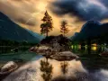 Dramatyczne zdjecia hdr: błyskawica nad skalistą wyspą z drzewami na środku jeziora, otoczonego górami.