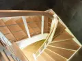 Drewniane schody kacze z białymi balustradami i metalowymi poręczami, prowadzące w dół.