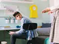 Nastolatek z telefonem w ręku, słuchający rodzica. Czyżby przypominano mu o obowiązkach 16 latka w domu?