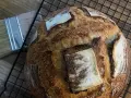 Chleb pszenno żytni na zakwasie, pachnący świeżością, czeka na ostygnięcie. Obok pędzel do pieczenia.