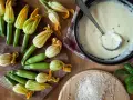 Flores de calabacín frescas y una salsa cremosa en una sartén.