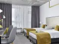 Pokój hotelowy z dwoma łóżkami, biurkiem i kwiatami. Idealne miejsce na wcześniejsze zameldowanie w hotelu.