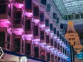 Wnętrze statku Silja Line z rzędami kabin oświetlonych różowym światłem i wiszącymi żyrandolami.
