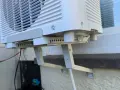 Klimaanlage mit Halterung und Kabeln. Der Kondenswasser Abfluss ist hier nicht sichtbar, aber die Einheit ist für die Ableitung vorbereitet.