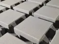 Szare, betonowe kostki brukowe ułożone w rzędach, gotowe do budowy ścieżki. Różne rodzaje kostki brukowej czekają na zastosowanie.
