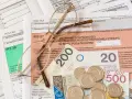 Okulary na dokumentach podatkowych PIT i pieniądzach. Zrozumienie, z czego wynika niedopłata podatku, wymaga analizy tych dokumentów.