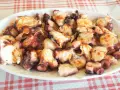 Pulpo a la gallega servido en plato blanco sobre mantel a cuadros rojos y blancos.