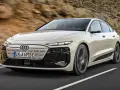 Jasnoszary Audi A6 e-tron z czarnymi akcentami jedzie po drodze.
