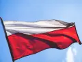 Flaga Polski, biało-czerwona, powiewa na tle błękitnego nieba.