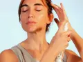 Mujer se aplica bruma facial para refrescar e hidratar su piel. Descubre para que sirve la bruma facial y luce un rostro radiante.