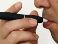 Persona usa un dispositivo IQOS. Las opiniones médicas sobre IQOS son variadas, pero este dispositivo calienta tabaco en lugar de quemarlo.
