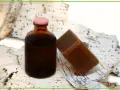Brązowa buteleczka z płynem i kostka mydła na tle kory brzozowej. To naturalne produkty, a dziegieć co to? To właśnie taki ciemny, aromatyczny produkt.