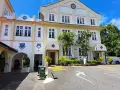 The imposing facade of Saint Benedict's Monastery, bathed in sunlight, features a clock tower and arched entrances.