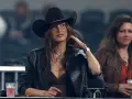 Mujer con sombrero tejano y chaqueta de cuero, disfrutando de un evento. Se aprecian otros tipos de tejanos en el público.