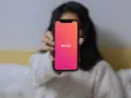 Osoba trzyma telefon z widocznym logo Tindera. Chcesz wiedzieć, jak sprawdzić, czy ktoś ma Tindera?