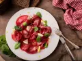 Bresaola affettata finemente, guarnita con spinacini freschi e spicchi di limone. Un'idea semplice su come condire la bresaola per un antipasto leggero.