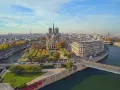Vista aérea de la Île de la Cité en París, con la majestuosa Catedral de Notre Dame en el centro, rodeada de edificios históricos y el río Sena.