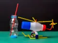 Helikopter z butelki i słomek obok butelki z czerwoną słomką.
