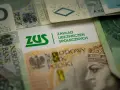 ZUS na tle polskich banknotów. Symbolizuje świadczenie rehabilitacyjne po ustaniu zatrudnienia, wsparcie finansowe w trudnych chwilach.