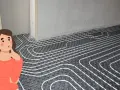 Una mujer pensativa observa la instalación de un sistema de suelo radiante, imaginando el confort que proporcionará.