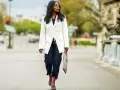 Mujer con un look smart elegant, lleva un blazer blanco, jeans oscuros y sandalias de diseño.