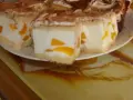 Sernik z bitą śmietaną siostry Anastazji, z kawałkami brzoskwini, posypany kakao. Pyszny deser na talerzu.