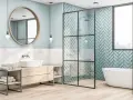 Salle de bain moderne avec baignoire îlot, douche vitrée et lavabo sur meuble en bois. Le mur derrière la douche est recouvert de **faïence** bleu sarcelle en chevrons.