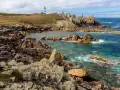 Phare noir et blanc sur une côte rocheuse et sauvage d'Ouessant. Combien de temps pour visiter Ouessant ? Une journée suffit pour admirer ce paysage.