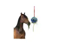 Un cheval mange de l'herbe d'une balle suspendue, un concept pour fabriquer un distributeur automatique de nourriture pour chevaux.