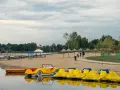 Żółte rowerki wodne i łódki czekają na plaży. Idealne miejsce na wypoczynek, jak na Mazurach blisko Warszawy.