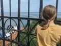 Dziewczynka podziwia widok z najwyższej latarni morskiej w Polsce. Widać morze, port i statki.