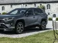 Szary Toyota RAV4 Hybrid przed kamiennym budynkiem. Zastanawiasz się, ile kosztuje Toyota RAV4 Hybrid?