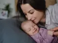 Mama całuje śpiące dziecko. Wkrótce wybierzemy dla niej słodkie imiona dla dziewczynki.