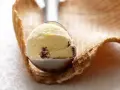 Ein Löffel cremiges Eis mit Rosinen und einem Hauch Rum ruht auf einem Waffelrand.