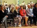 Uczestnicy siedzą na krzesłach, słuchając uważnie. Wśród nich widać osoby, które mogą być na radzie pedagogicznej, w tym kobiety w eleganckich strojach i mężczyzn w garniturach.