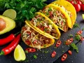 Pyszne tacos w stylu tex-mex, z mielonym mięsem, serem, pomidorami i awokado, podane z limonką i papryczkami chili.