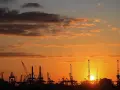Silhouetten von Kränen im Hamburger Hafen bei Sonnenuntergang. Perfekt für die Pfingstferien in Hamburg.